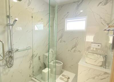 Modern bathroom with marble walls, glass shower, and contemporary fixtures