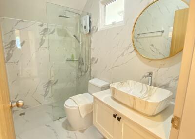 Modern bathroom with marble walls and floor, glass shower enclosure, and vanity with vessel sink
