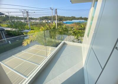 Modern balcony with glass railing and surrounding greenery