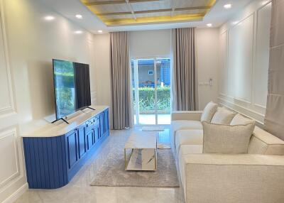 Bright and modern living room with a large TV, comfortable beige sofa, and glass coffee table