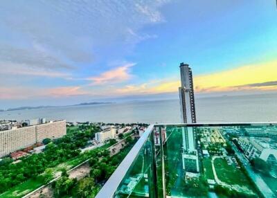 View from a balcony overlooking the ocean and a cityscape at sunset