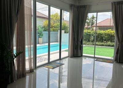 Living room with floor-to-ceiling windows and view of pool and garden