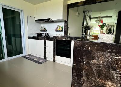 Modern kitchen with marble countertops and a view into the living area