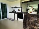 Modern kitchen with marble countertops and a view into the living area