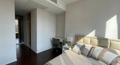 Modern bedroom with a bed, desk, and natural light