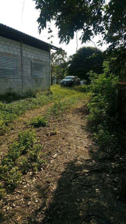 Pathway beside a concrete building with car in the background