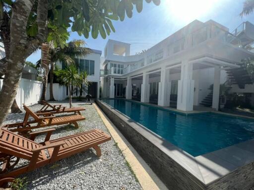 Swimming pool with lounge chairs and modern house