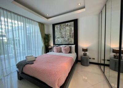 Modern bedroom with large windows, pink bedding, and mirrored wardrobe