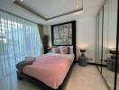 Modern bedroom with large windows, pink bedding, and mirrored wardrobe