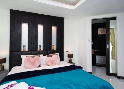 Modern bedroom with stylish black accent wall, cozy double bed, and decorative pillows