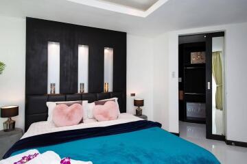 Modern bedroom with stylish black accent wall, cozy double bed, and decorative pillows