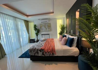 Modern bedroom with large windows, stylish decor, and spacious layout