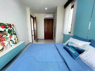 Well-lit bedroom with blue bedding, artwork, and air conditioning