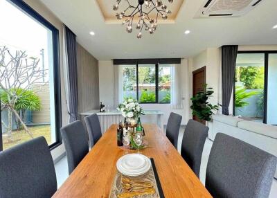 Modern dining area with wooden table, black chairs, and decorative chandelier