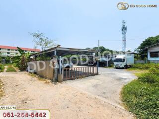 Gated entrance of a property with parked trucks and nearby buildings