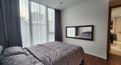 Bedroom with a large window, double bed, and wall mirror