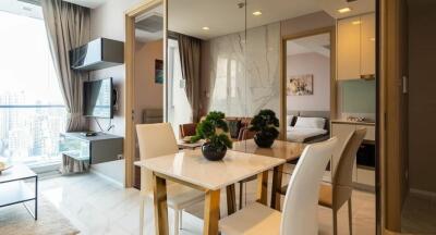 A well-lit modern apartment living and dining area with a view of adjacent bedroom