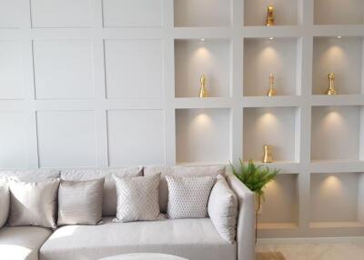 Well-decorated living room with a gray couch and wall shelving with decorative items