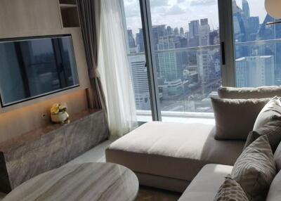 Modern living room with a large sofa, flat-screen TV, and a city view