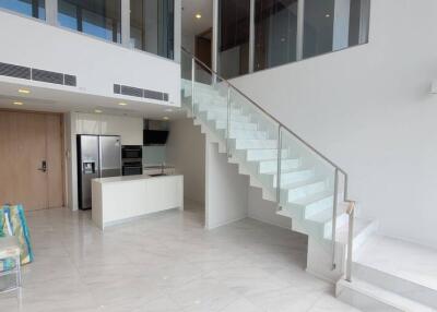Modern living area with glass staircase and kitchen