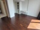 Empty bedroom with hardwood flooring and sunlight from large windows