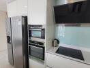 Modern kitchen with built-in appliances and stainless steel refrigerator