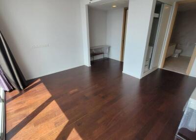 Bright bedroom with dark hardwood floors and large windows