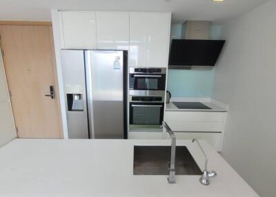 Modern kitchen with white cabinets, stainless steel refrigerator, built-in oven, induction cooktop, and sink