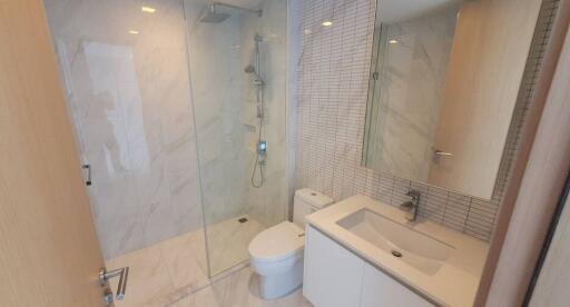 Modern bathroom with glass shower enclosure, floating vanity, and large mirror