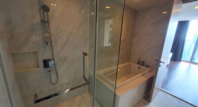 Modern bathroom with shower, bathtub, and marble tiles