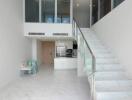 Modern living area with white tiled flooring, staircase, and open kitchen