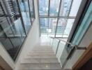 modern staircase with glass railings and city view