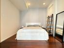 Modern minimalist bedroom with bed, full-length mirror, shelves, and an adjoining bathroom