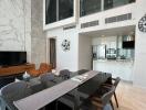 Modern open living area with high ceiling, dining table, and kitchen