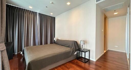 Modern bedroom with hardwood floor and dark curtains