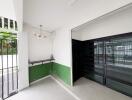 Modern entryway with green and white walls, lighting fixture, and black metal gate