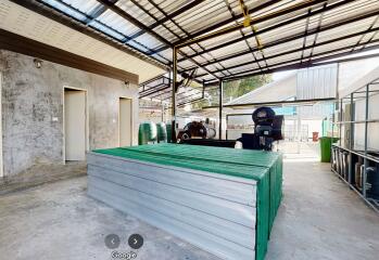 Outdoor area with a covered roof, storage containers, and industrial equipment