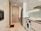 Modern kitchen with white cabinetry, appliances, and a door leading outside