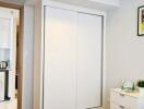 Bedroom with white wardrobe, small dresser, and view of a laundry area