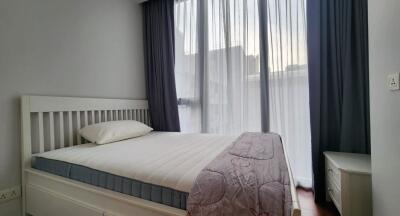 Bedroom with a large window and a bed with white linens