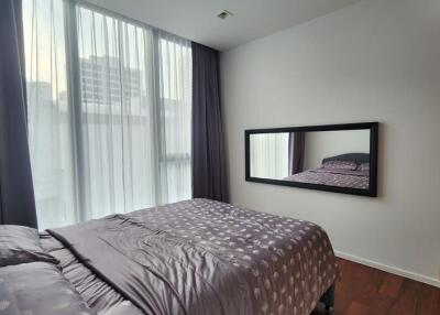 Modern bedroom with large window, curtain, and a bed