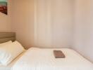 Small bedroom with a bed, white linens, and a neatly folded towel