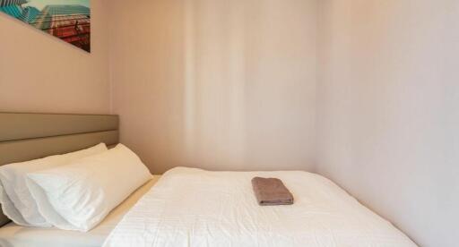 Small bedroom with a bed, white linens, and a neatly folded towel