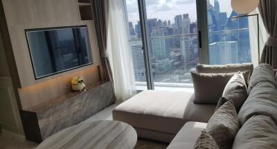 Modern living room with a large sectional sofa and a mounted TV with a cityscape view