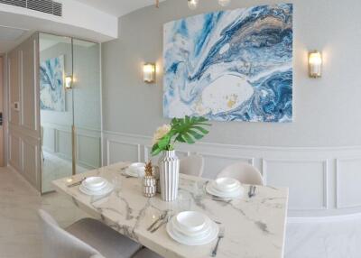 Modern dining area with marble table, decorative wall art, and elegant lighting