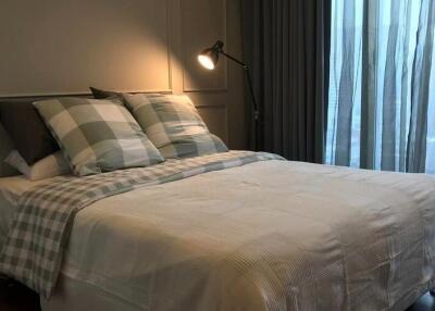 Cozy bedroom with a well-lit reading lamp and large window with sheer curtains