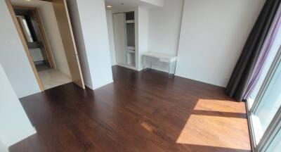 Spacious bedroom with dark wood flooring and large window