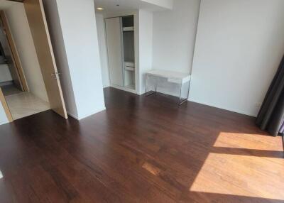 Unfurnished bedroom with dark wooden floor, large windows, white walls, and a small desk