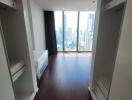 Walk-in closet facing bedroom with large windows and city view