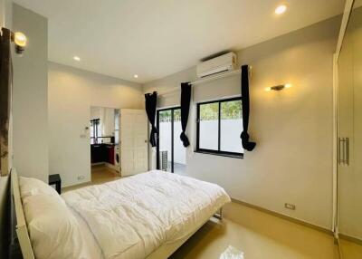 Bright bedroom with white walls, large bed, air conditioner, and wardrobe